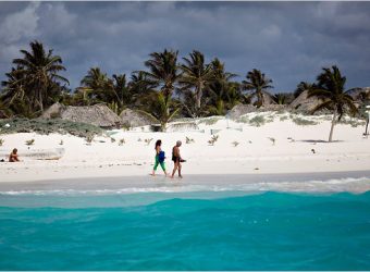 Tourists walk along the beach in front of Zazilkin, a hotel with rustic cabanas in Tulum, on the Yucatán Peninsula. Photo by Michael Nagle.