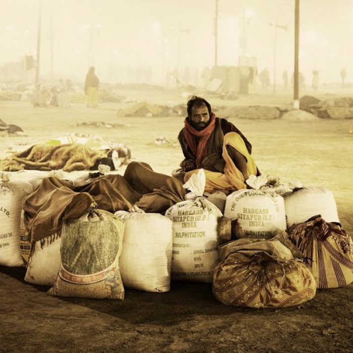 A man guards a pile of clothing at the Kumbh, where 30 million people converge in India.